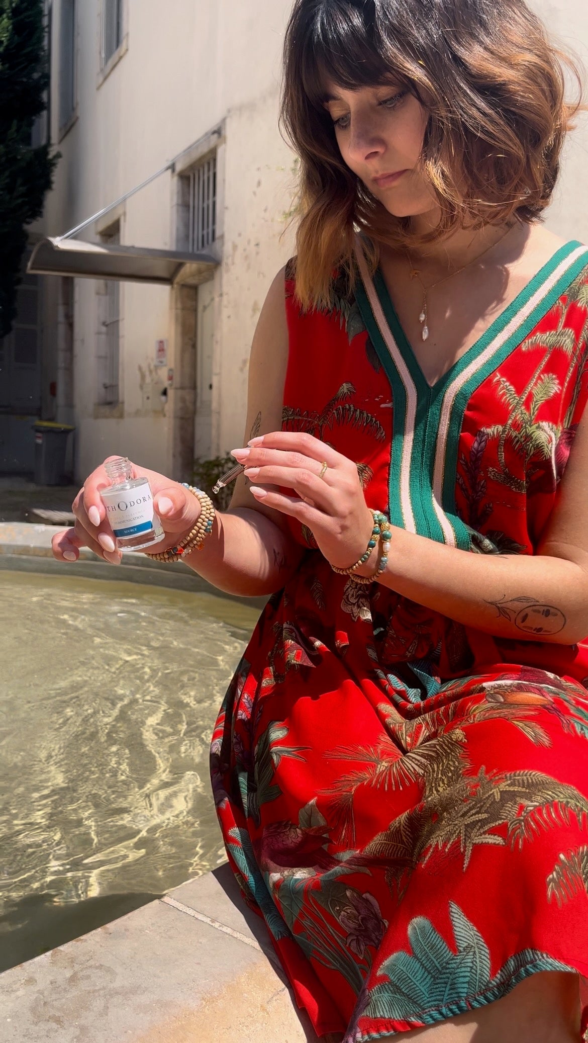 Egérie portant les bracelets de la collection bleue, auprès d'une fontaine