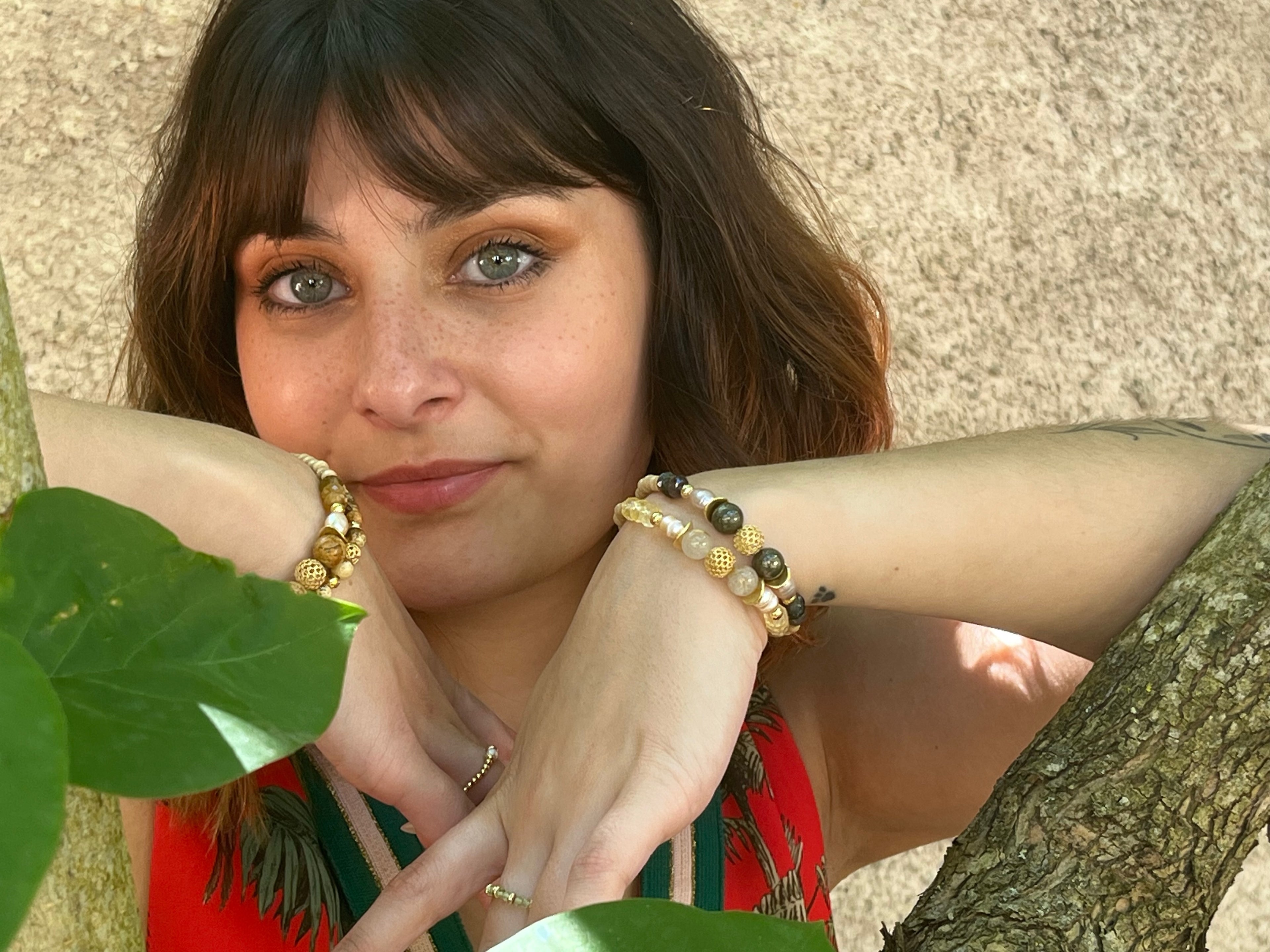 Égérie auprès d'un arbre présentant les bracelets Lithodora de la collection Poema